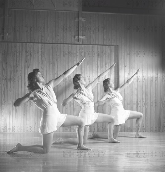 Gymnastics in the 1940s. Three young female gymnasts are practicing together and doing the same