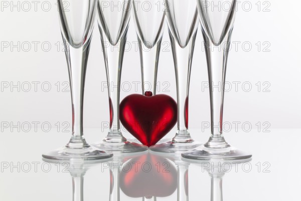 Five champagne glasses and red heart on a glass plate