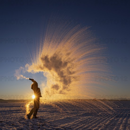 Woman throws hot water into the air that freezes into ice crystals, Mpemba effect, Unterallgäu,
