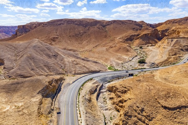 Asphalt highway meanders among the hills. Dead Sea mud has healing properties. Drone filming.