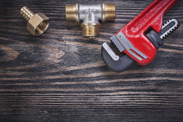 Monkey wrench brass equal tee hose nipple on wooden background plumbing concept