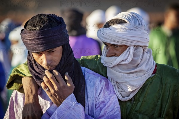 Two men in traditional dress and turbans, one puts his arm around the other, The traditional Tuareg