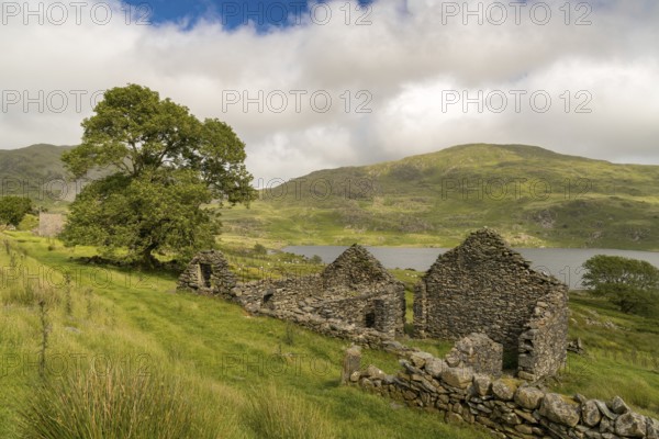 Grey clouds over Llyn Cwmystradllyn with a derelict ruin on the shore, near Penmorfa, Gwynedd,