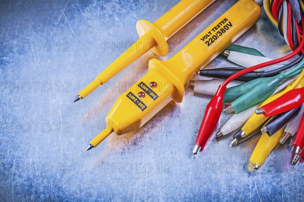 Yellow electrical tester set of multicolored crocodile clip cables on metallic background