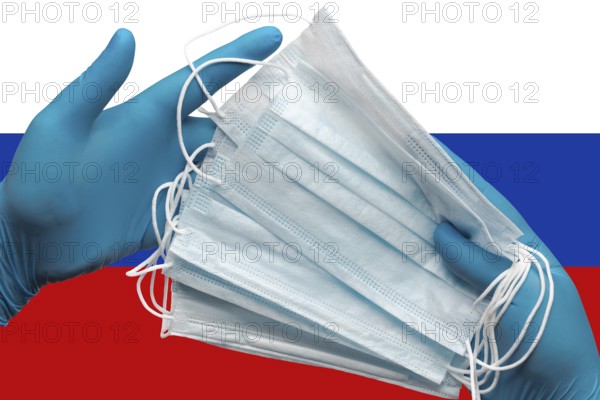 Doctor holding face masks in hands surgical blue gloves on background national flag of Russia.