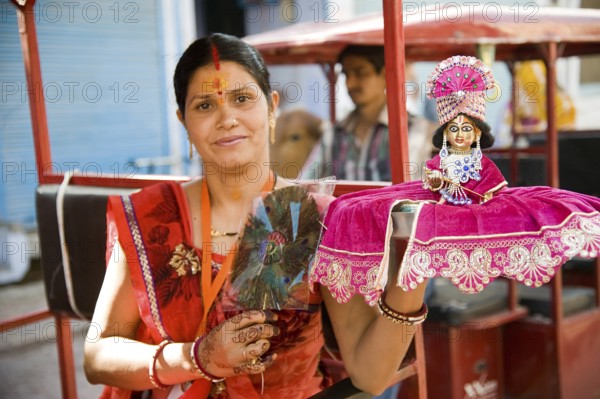 Woman holding krishna idol on hand, mathura, uttar pradesh, india, asia