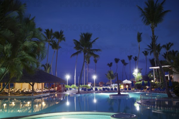 Tropical resort at night. View with empty restautant, huge palms and electric lights reflecting in