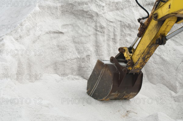 Excavator digging pile white salt
