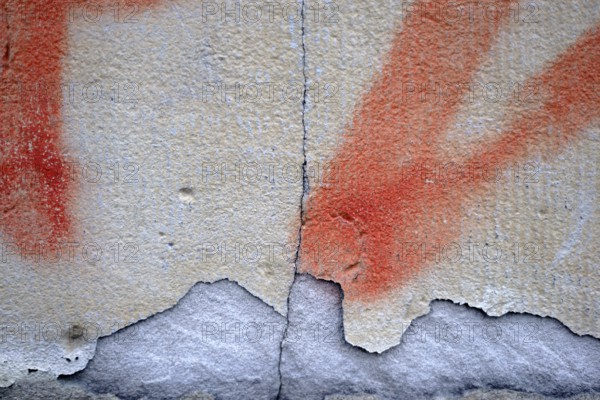 Close-up of a wall with a chipped and painted layer of plaster