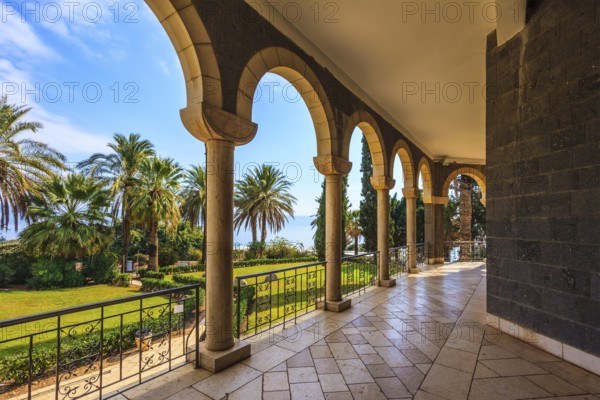 The basilica is surrounded by gallery with columns. Subtle shade of palms. Church Sermon on the