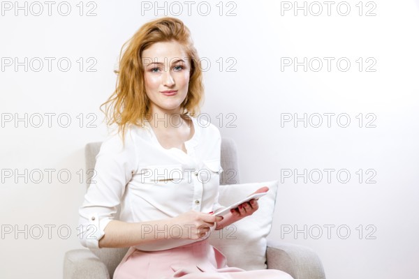 People, technology and education concept - young student woman sitting on a chair and using a