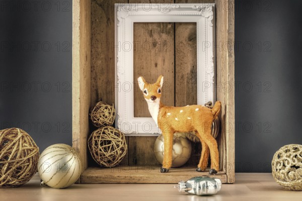 An image of a Christmas decoration wooden box with deer golden balls and a white frame