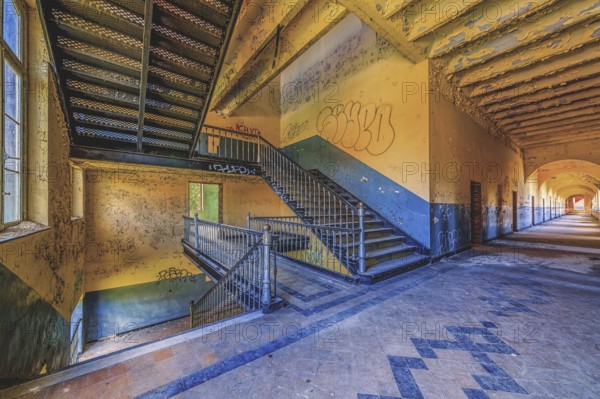 Long, deserted corridor with stairs and graffiti on the walls, Prison H11, Lost Place, Verviers,