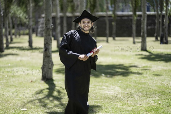 Portrait, student and happy man at graduation with certificate in university campus for success and