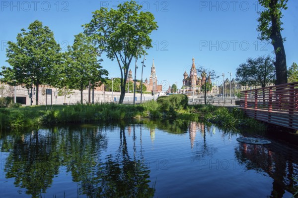 Zaryadye park and Kremlin fortress and St. Basil 's Cathedral in Moscow with pond and reflections,