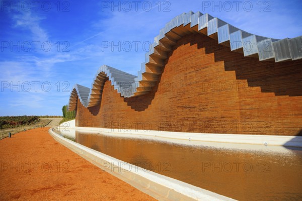 Wave-shaped winery roof. Fragment of the facade is reflected in the pool. Winery - bodega Bodegas