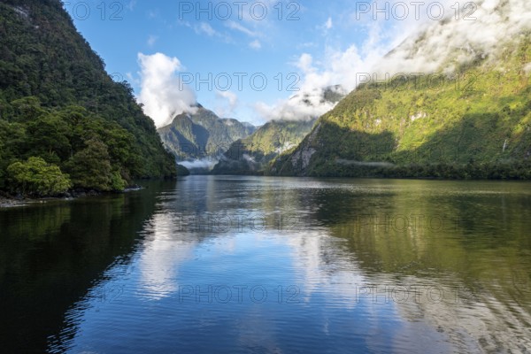 A new morning dawning at Doutful Sound, clouds hanging low in the mountains, South Island of New