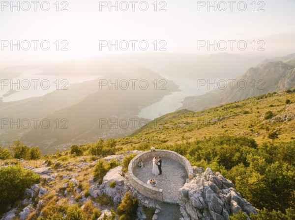 Bride and groom standing on the observation deck on the mountain against the backdrop of the Bay of