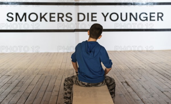 Teenager smoking and message on wall - Smokers die younger. No smoking concept with child. Casual