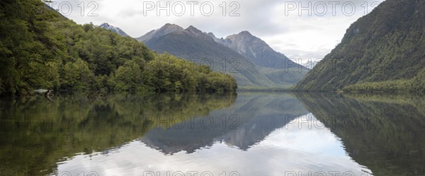 Tranquil lake Gunn in Fiordland National Park, landscape reflecting on the water surface, South