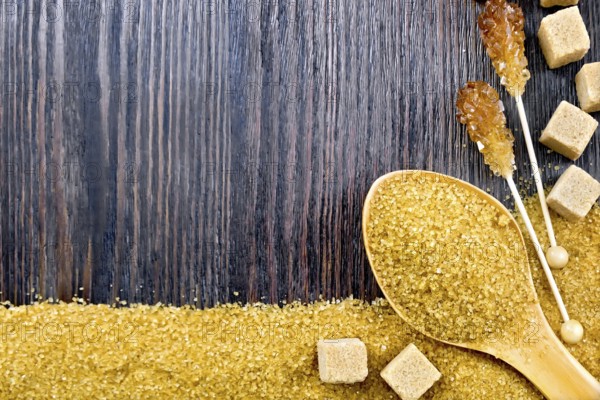 Sugar brown granules in a spoon, cubes and crystals on a stick in the form of a frame on the