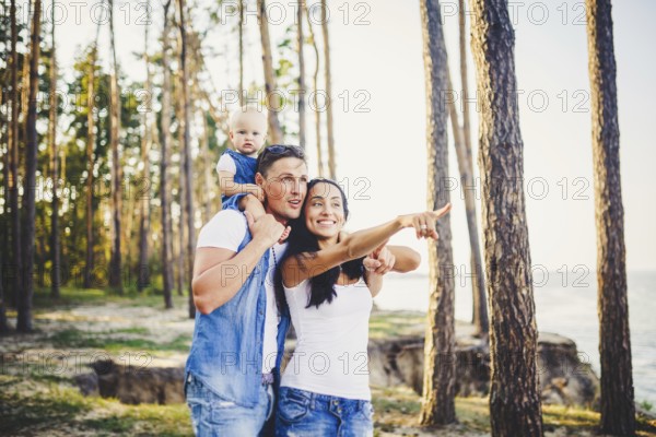 Happy young family of three people resting in a park outside the city. daughter sits at daddy on