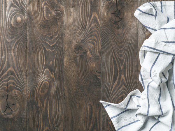 View from above on brown wooden table with linen kitchen towel or textile napkin. Blue tablecloth