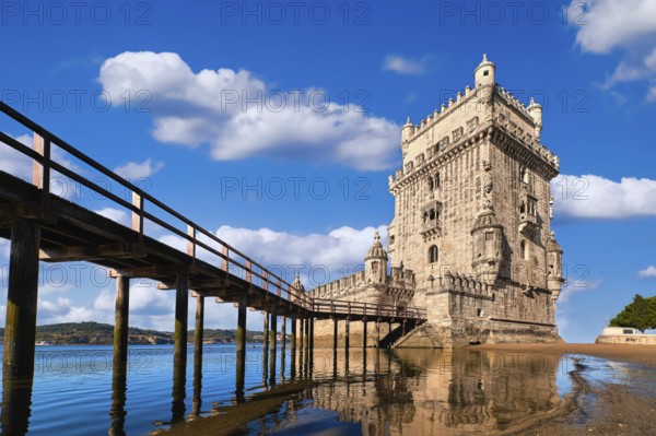 Belem tower and wooden bridge to it, Lisbon, Portugal at blue summer day sky with clouds. Medieval