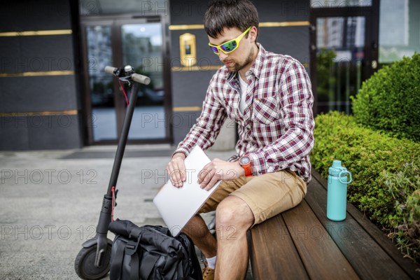 Young caucasian man in casual clothes freelancer uses eco-friendly electric transport scooter. Male