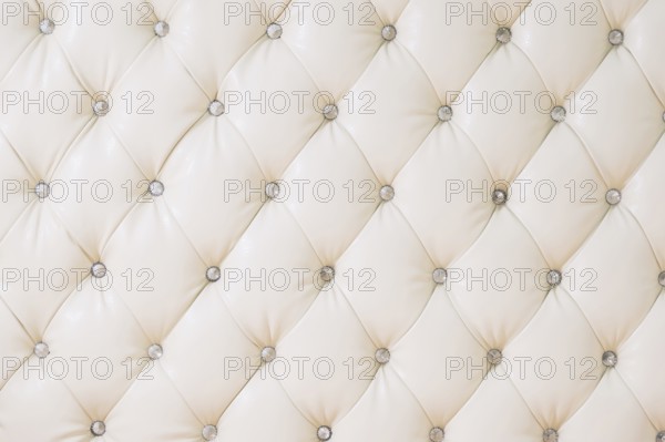 Beige soft tapestry pattern background with symmetrical buttons on the corners of diamonds. Soft