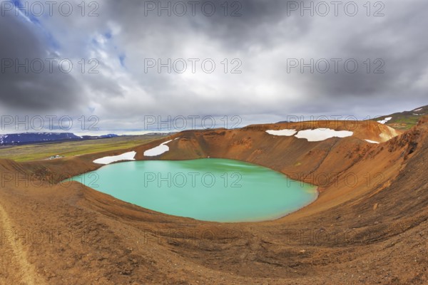 Lake water bright green color. On the shores lie snowfields from last year. Picturesque lake in the