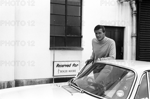 Sir Roger Moore, 1927-2017 during the filming of the tv-series The Saint, posing with a Volvo P1800