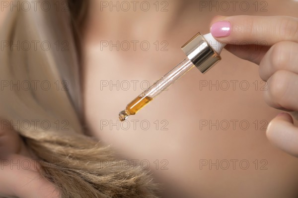 A closeup view of a dropper filled with luxurious hair oil, emphasizing its nourishing and