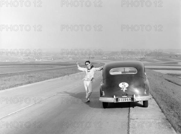 Vaction in Italy in the 1951. A man at his car during a car vacation trip in Italy. He has stopped