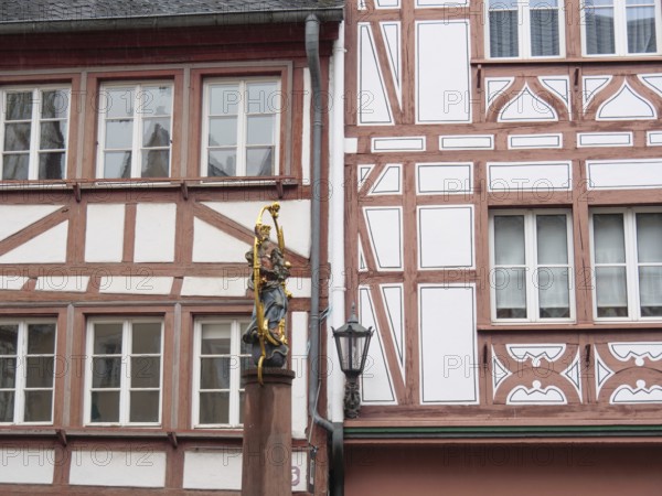 Half-timbered wall with statue of the Virgin Mary standing next to a street lamp post, mainz,