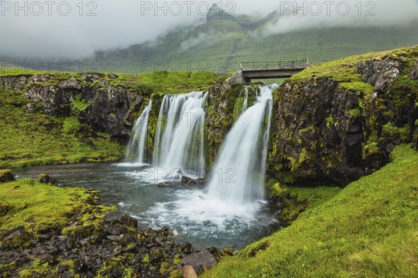 Threaded full-flowing waterfall on the grassy mountains. Iceland - country of mountains, rivers and