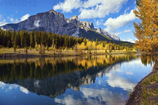 Outskirts of Canmore. Lush autumn in the Canadian Rockies. Cumulus clouds reflected in the smooth
