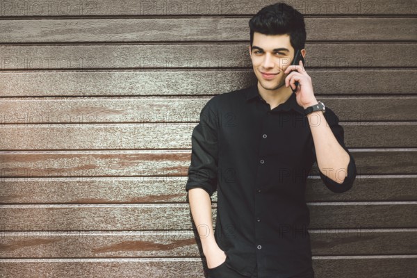 Portrait model young handsome male suspect Turkish middle eastern brunette in black shirt uses hand