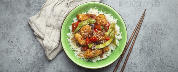 Asian sweet and sour sticky chicken with vegetables stir-fry and rice in ceramic bowl with