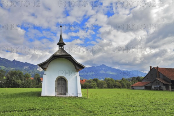 Small rural chapel on a green meadow. Picturesque forged door decorated rows of round rivets. A