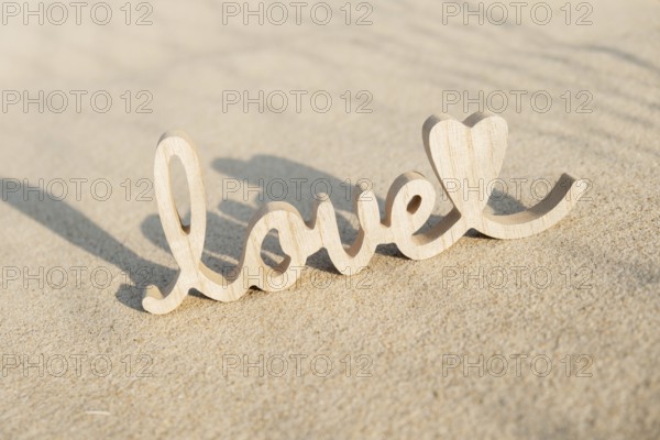 Wooden word love on sandy beach background. Concept of romantic holiday anniversary, proposal,