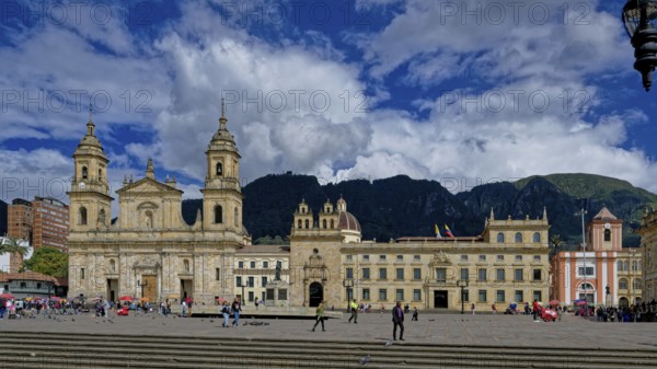 A historic cathedral and buildings surround a bustling plaza with people walking under a dramatic