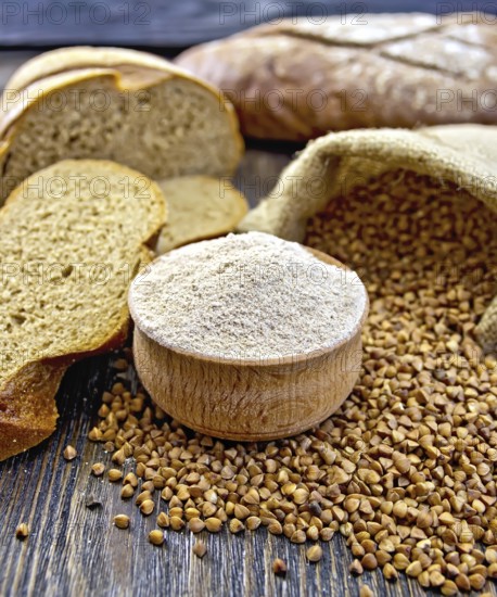 Buckwheat flour in a wooden bowl, buckwheat in the bag, the bread slices on a wooden boards