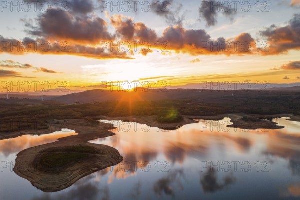 Drone aerial view of a lake reservoir of a dam with perfect reflection on the water of the sunset
