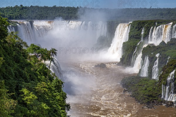 View to Devil's Throat and Iguazu Falls gorge with brown river, white cascading falls and lush