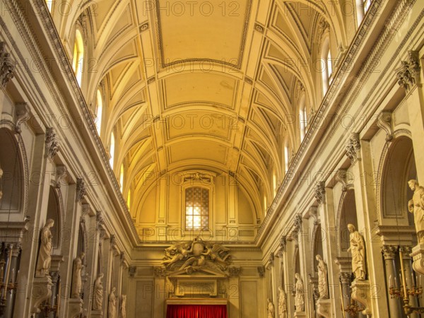 Brightly lit nave of a baroque church, decorated with high ceilings and long rows of columns,