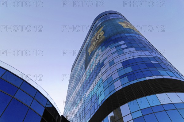 A modern skyscraper with a blue reflective glass facade and advertising, illuminated in daylight,