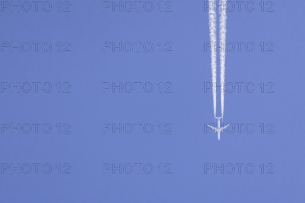 Airbus aircraft of Qatar airways flying across a blue sky with a vapour trail or contrail behind,