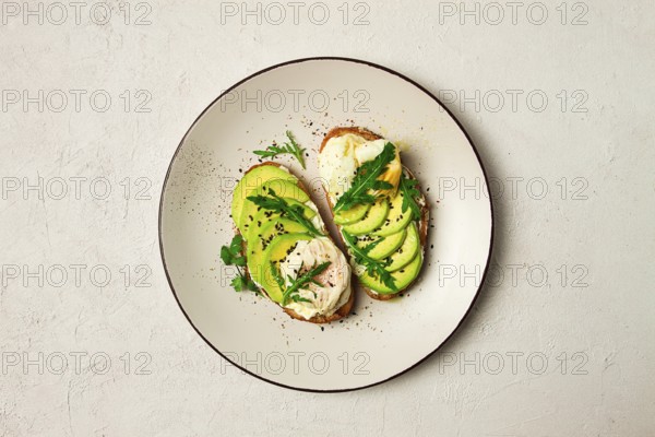 Sandwich with cream cheese, sliced avocado and boiled egg, arugula, on grainy bread, homemade,