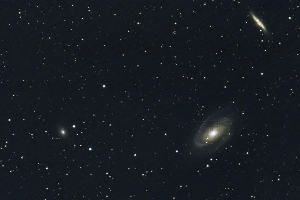 Two spiral galaxies (M 81 and M 82) and other galaxies, embedded in a star-studded deep space,